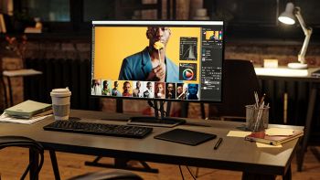 Monitor da ufficio widescreen con software di fotoritocco aperto su scrivania