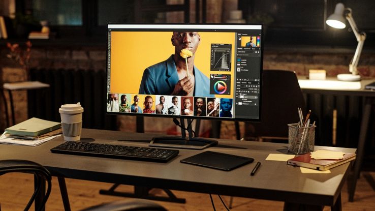 Monitor da ufficio widescreen con software di fotoritocco aperto su scrivania