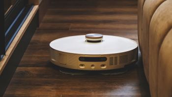 Robot aspirapolvere lavapavimenti con LiDAR che pulisce il pavimento vicino al divano.