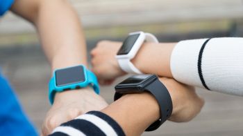 Smartwatch al polso di tre amici, fitness tracker per attività e salute.