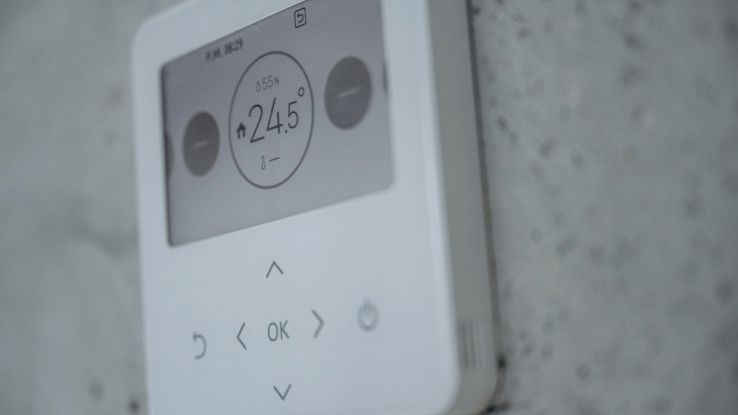 Termostato smart Wi-Fi montato a muro con display che indica 24,5 °C.