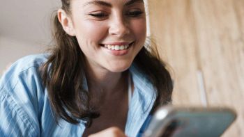 Una ragazza usa uno smartphone e sorride