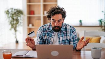 Un uomo al pc con la carta di credito