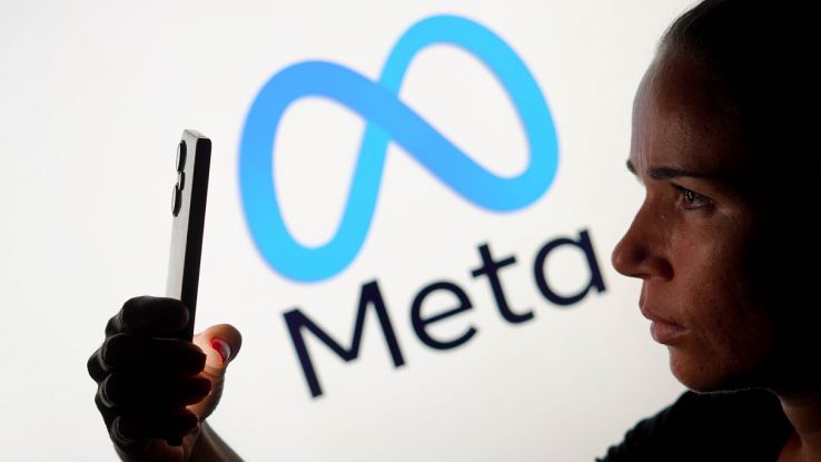 Persona impugna uno smartphone sfondo logo Meta