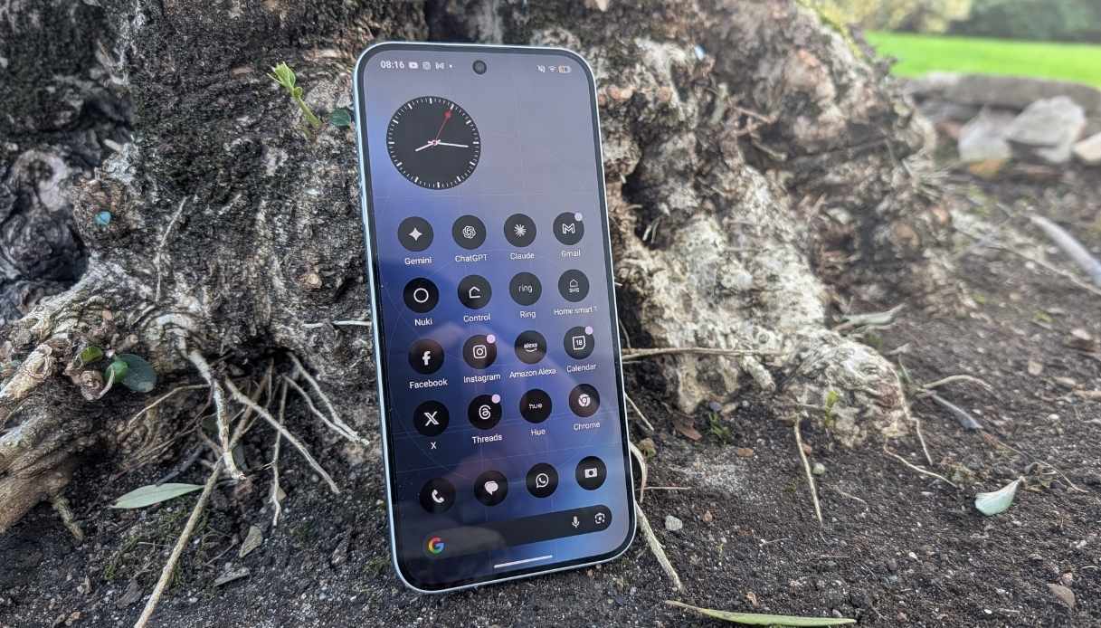 Nothing Phone (4a) Pro silver appoggiato su corteccia con schermo AMOLED acceso.