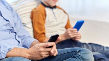 Due smartphone in mano a bambino e uomo adulto