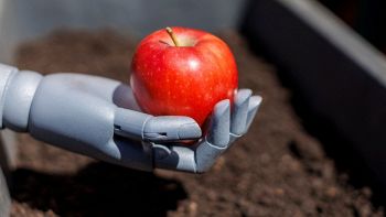 Mano robotica stringe una mela