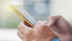 Mani di uomo che reggono uno smartphone dorato