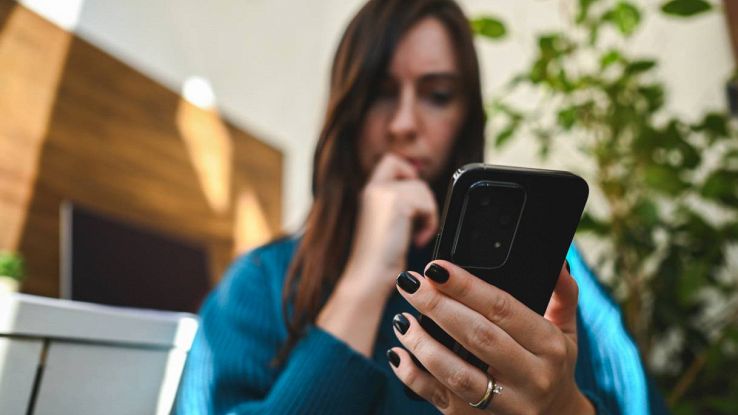 Una donna preoccupata guarda lo smartphone