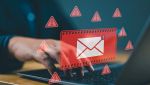 Un uomo digita sulla tastiera di un pc con alert di posta elettronica