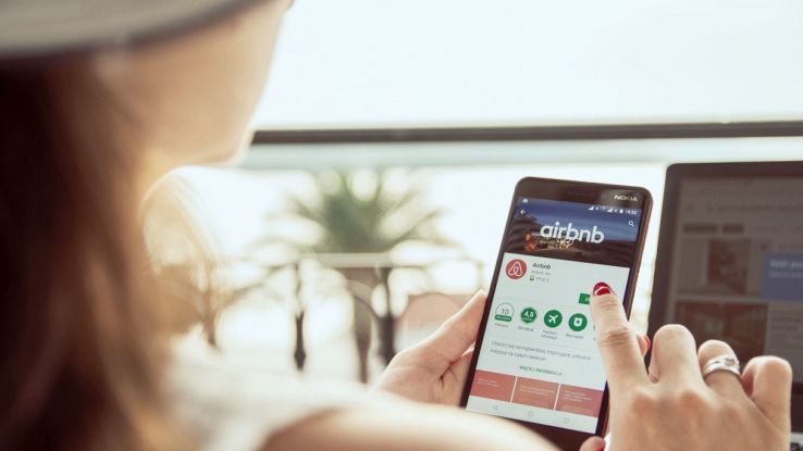 Donna scorre pagina Airbnb su smartphone