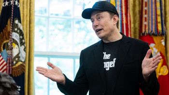 Elon Musk parla con cappellino e braccia aperte