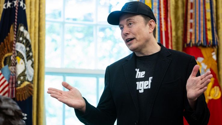Elon Musk parla con cappellino e braccia aperte