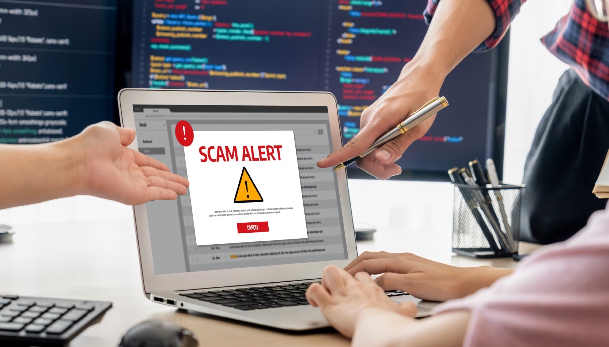 https://wips.plug.it/cips/tecnologia/cms/2026/07/mani-indicano-monitor-computer-scam-alert.jpg