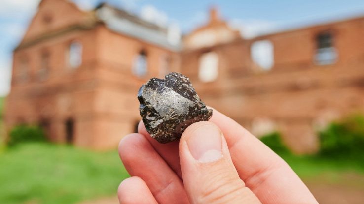 Edificio sullo sfondo e frammento roccioso in mano