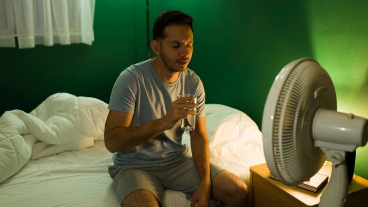 Uomo in pigiama beve davanti ventilatore