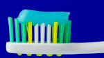 Spazzolino bianco giallo e verde con dentifricio azzurro