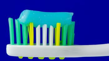 Spazzolino bianco giallo e verde con dentifricio azzurro