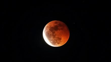 Cielo scuro con porzione di luna rossa