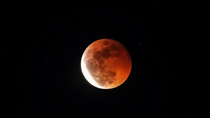 Cielo scuro con porzione di luna rossa