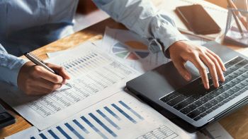 Un uomo controlla delle tabelle e dei grafici con un PC