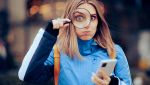 Una donna con smartphone e lente d'ingrandimento