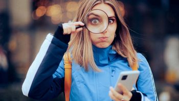 Una donna con smartphone e lente d'ingrandimento