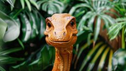 Sfondo vegetale con dinosauro arancio davanti