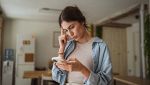 Donna con smartphone in mano lo guarda preoccupata