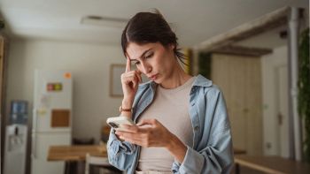 Donna con smartphone in mano lo guarda preoccupata