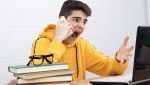 Ragazzo urla con smartphone davanti laptop