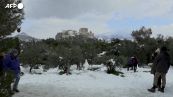 Gli abitanti di Atene si divertono con la neve sulle colline davanti all'Acropoli
