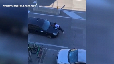 Scena da brivido: donna si aggrappa al cofano di un'auto in corsa