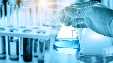 Mano di scienziato che tiene una provetta con un liquido all'interno in un laboratorio chimico