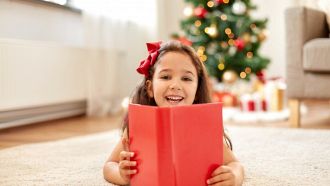 Una bambina di 4 anni con un libro dalla copertina rossa