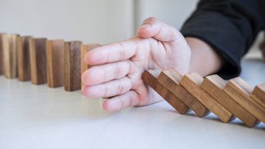 Uomo che previene la caduta di tessere del domino