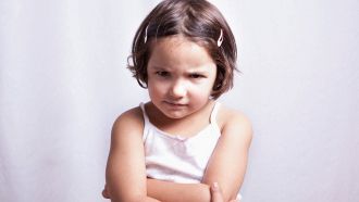 Bambina di 3 anni arrabbiata su sfondo bianco