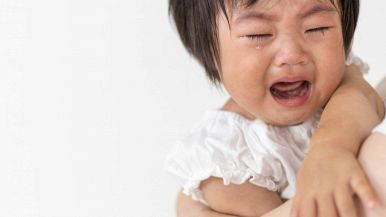 In primo piano sulla destra, una bambina di 2 anni con un caschetto scuro è in lacrime e urla presa dalla collera. Rabbia nei più piccoli