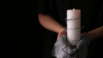 Una candela avvolta da filo spinato su panno con stella di David