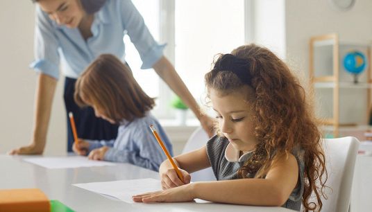 bambine disegnano sotto gli occhi della maestra