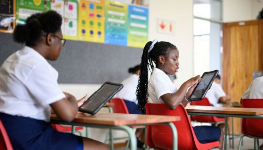 Ragazze studiano sui banchi di scuola con il tablet