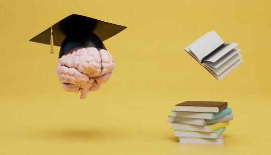 Cervello in un cappello per la laurea vicino a una pila di libri
