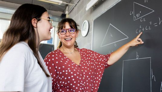 Professoressa insegna matematica a un'alunna alla lavagna