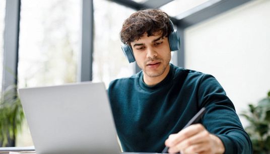 ragazzo ascolta un video e prende appunti