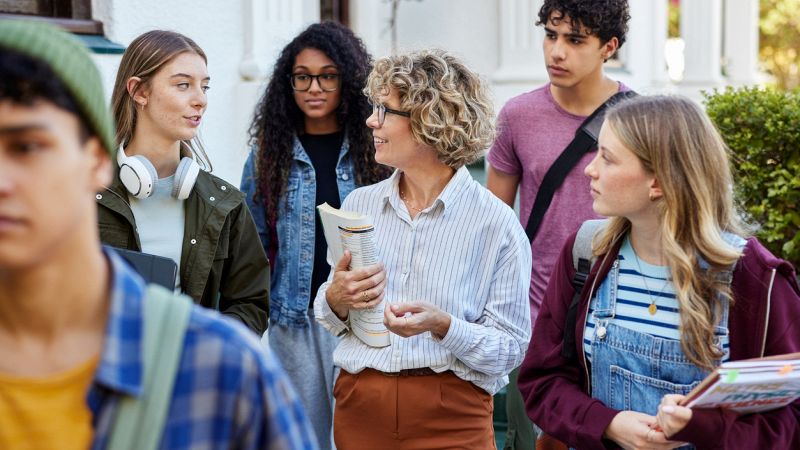 High school teacher walking with multiethnic students outside school