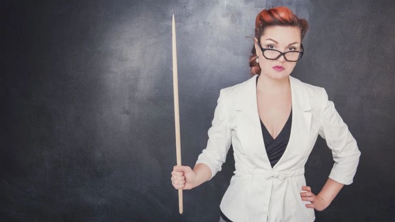 Professoressa con una bacchetta in mano e sguardo severo