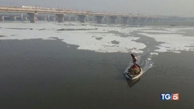 Fiume sacro indiano tra schiuma e rifiuti