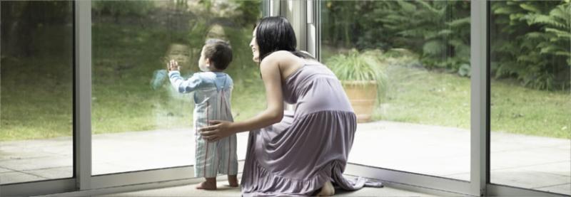 mamma e bambino che guardano fuori attraverso una porta finestra in vetro